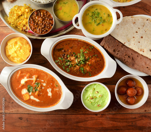 Assorted indian foods paneer butter masala,channa masala,roti and veg thali on wooden background. Dishes and appetizers of indian cuisine