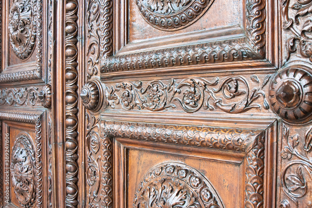 Detail of an old italian wooden carved door with floral decorati