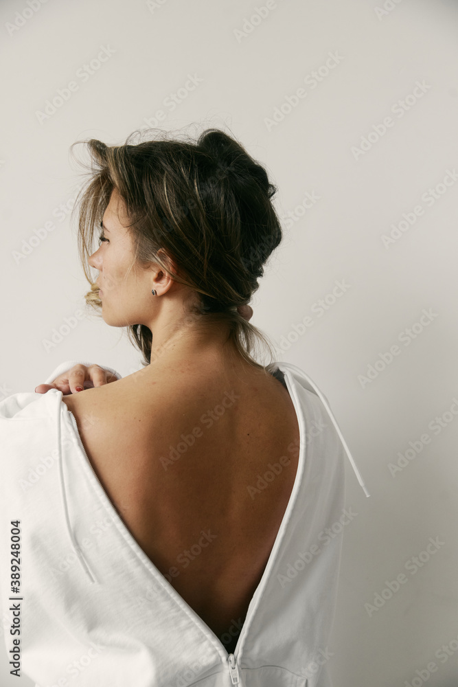 Portrait of beautiful young woman with brown hair and clean bronze skin without makeup on white background. Natural and healthy look. Neutral interior. Soft light. Portrait of beautiful young woman with brown hair and clean bronze skin without makeup on white background. Natural and healthy look. Neutral interior. Soft light.
