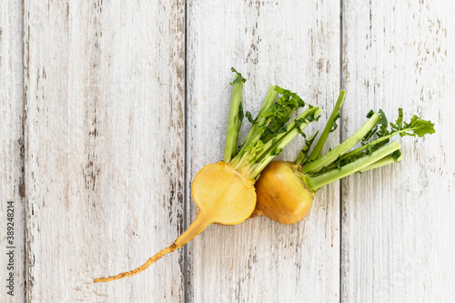 Cut yellow turnip with leaves on a white wooden background. Useful vitamins from root vegetables all year round