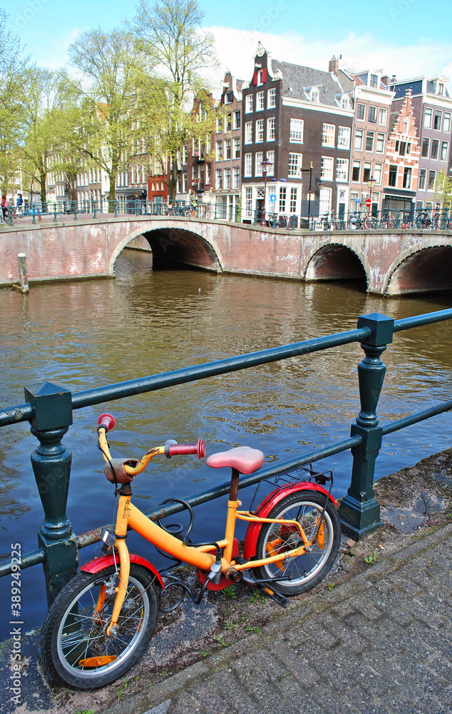 Children's bike on the canal embankment in Amsterdam