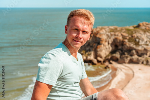 Portrait of a young handsome man on the beach with a rocky beach © KseniaJoyg