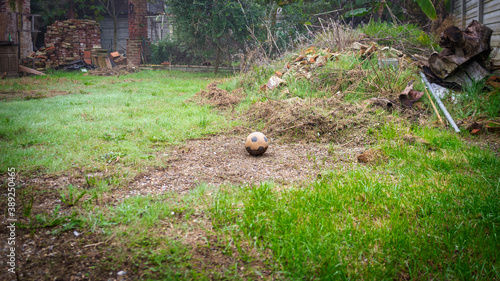 Old ruined soccer ball, abandoned in a wild meadow full of rubbish. Color image.