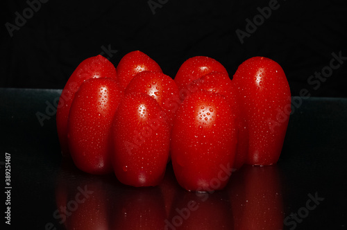 Close-up on wet cherry tomatoes. Drops of water and bright shiny red. black background with space for text