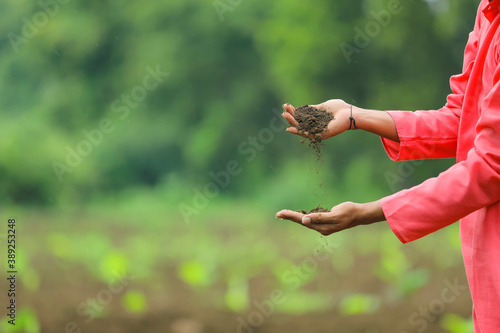 Indian farmer holding black soil in hand and analyze at agriculture field