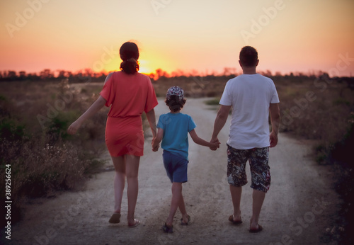 Black silhouettes Happy family with a child walking in the Park outdoors. A little boy holding hands of his parents against the backdrop of the setting sun. The concept of family happiness