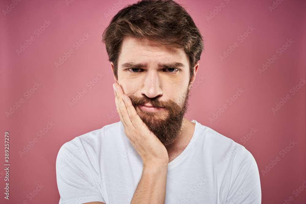 bearded man in white t-shirt emotions displeased facial expression studio pink background