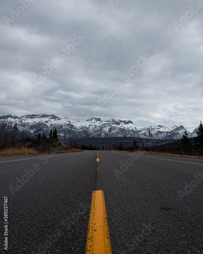 carretera con lineas intermitentes con montañas nevadas 