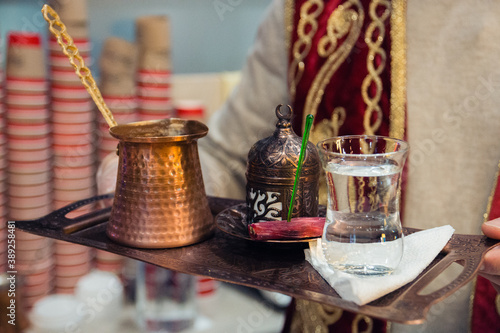 a man serves a tray of traditional Turkish coffee made on the sand in Turku, selective focus