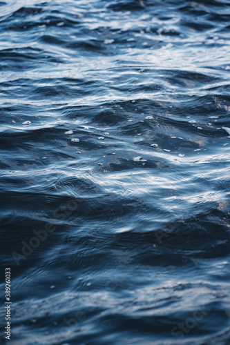 Close-up water surface, sun glare and blurred photo. Natural and abstract background.