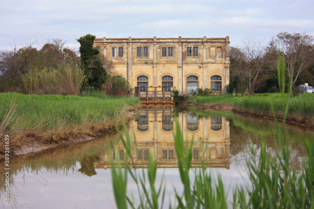 Obraz premium natural panorama with an ancient industrial structure the old dewatering building on the Arno river among the green grass