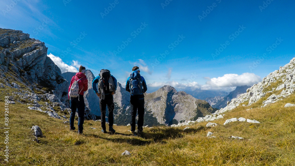 A couple of friends enjoying the Alpine landscape from Hochzin?dl peak in Austria. Steep, sharp mountains around her. Fall landscape - golden grass. Exploring and experiencing the nature. Friendship