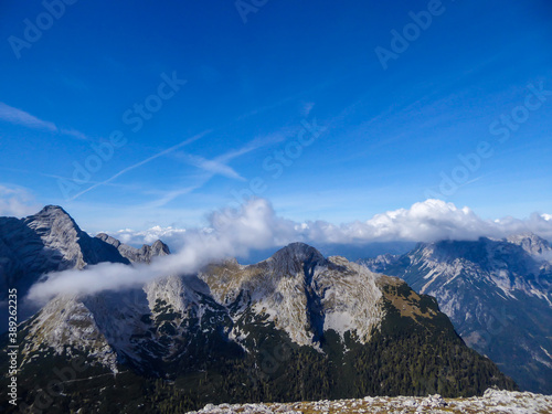 A panoramic view on a massive, stony mountains in Hochzin?dl region, Austrian Alps. There are endless mountains chains in the back. The slopes are overgrown with moss and grass. Sunny and bright day.