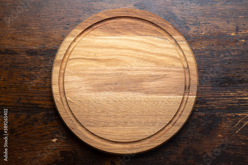Empty round cutting board on a wooden table. Space for text.