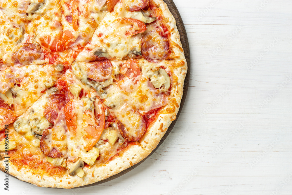 Delicious simple pizza with tomatoes, mozzarella and bacon on white wooden background.
