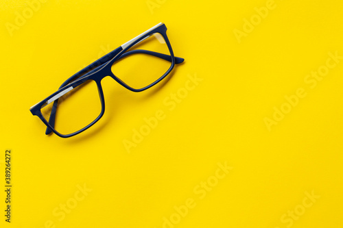 Fashionable glasses in blue frames for vision on a yellow background. Health concept.
