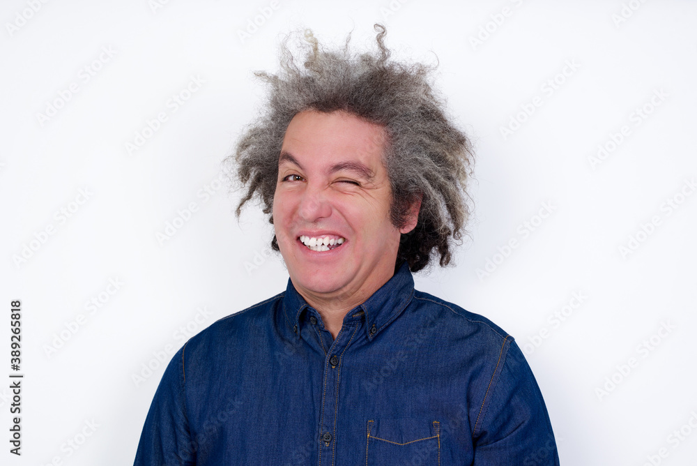 Coquettish Handsome mature caucasian man with afro grey hair standing over isolated white background smiling happily, blinking at camera in a playful manner, flirting with you. Coquettish Handsome mature caucasian man with afro grey hair standing over isolated white background smiling happily, blinking at camera in a playful manner, flirting with you.