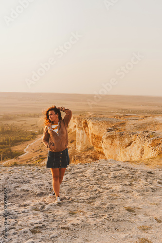 Portrait of a young woman on a mountain in an orange sunset