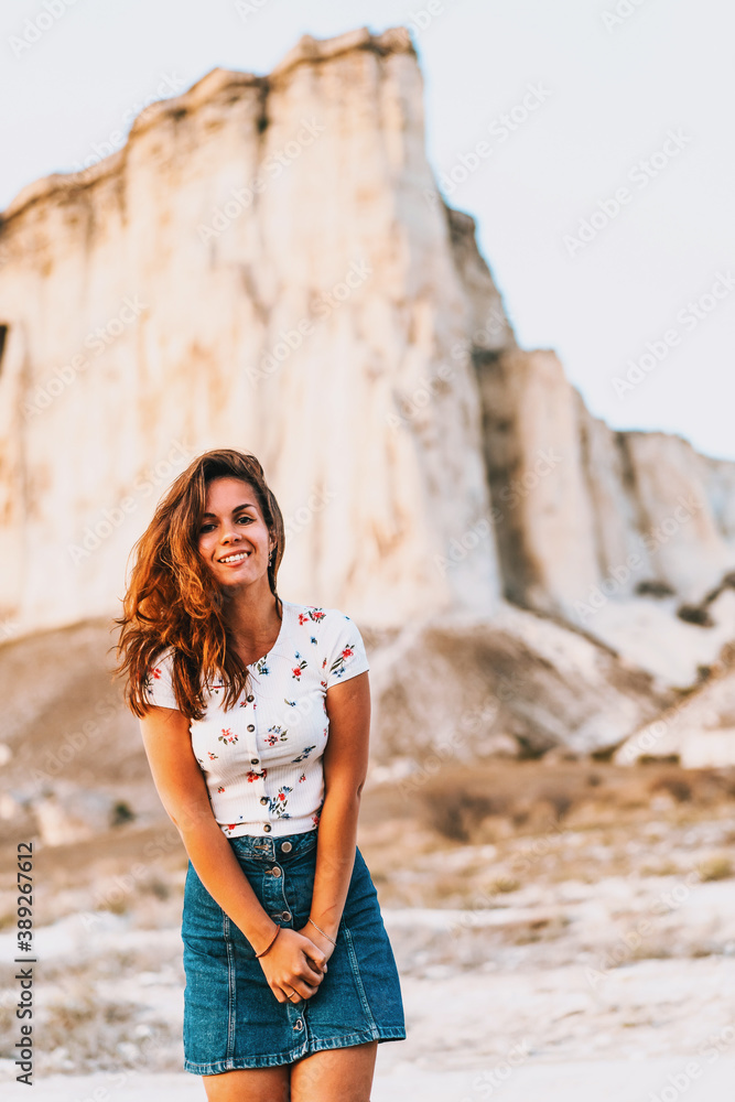 Portrait of a charming woman in a skirt at sunset on a White rock background in Crimea