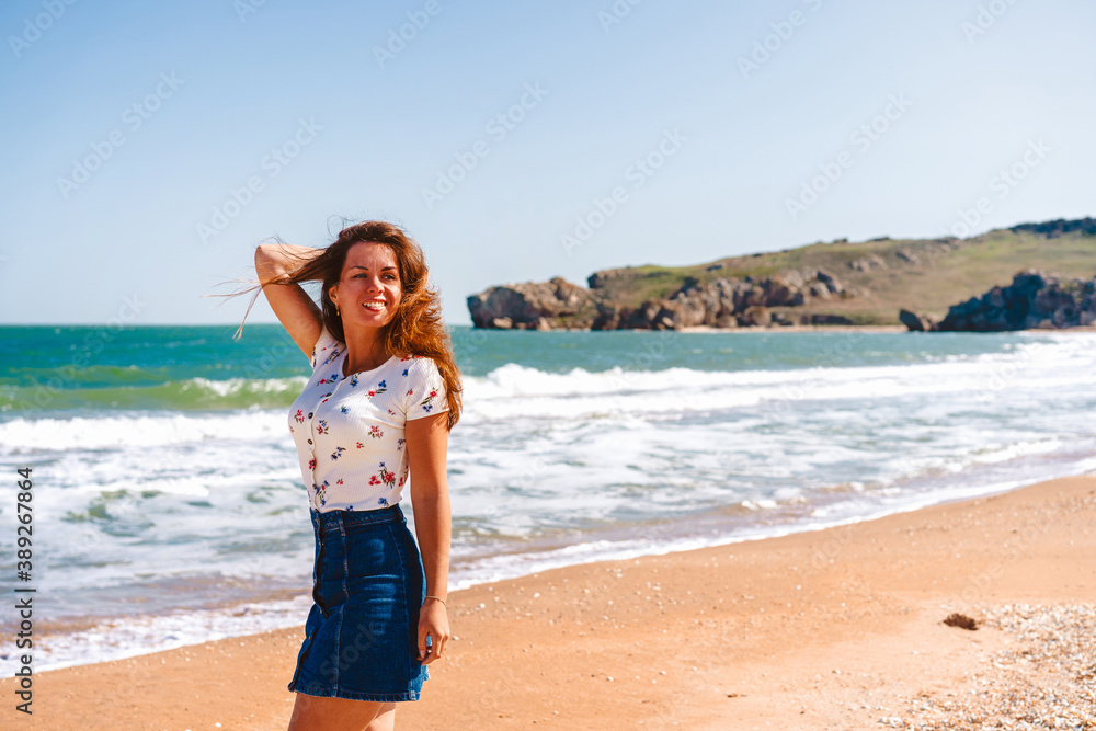 Beautiful young woman with long hair walks along the Black sea on the beach