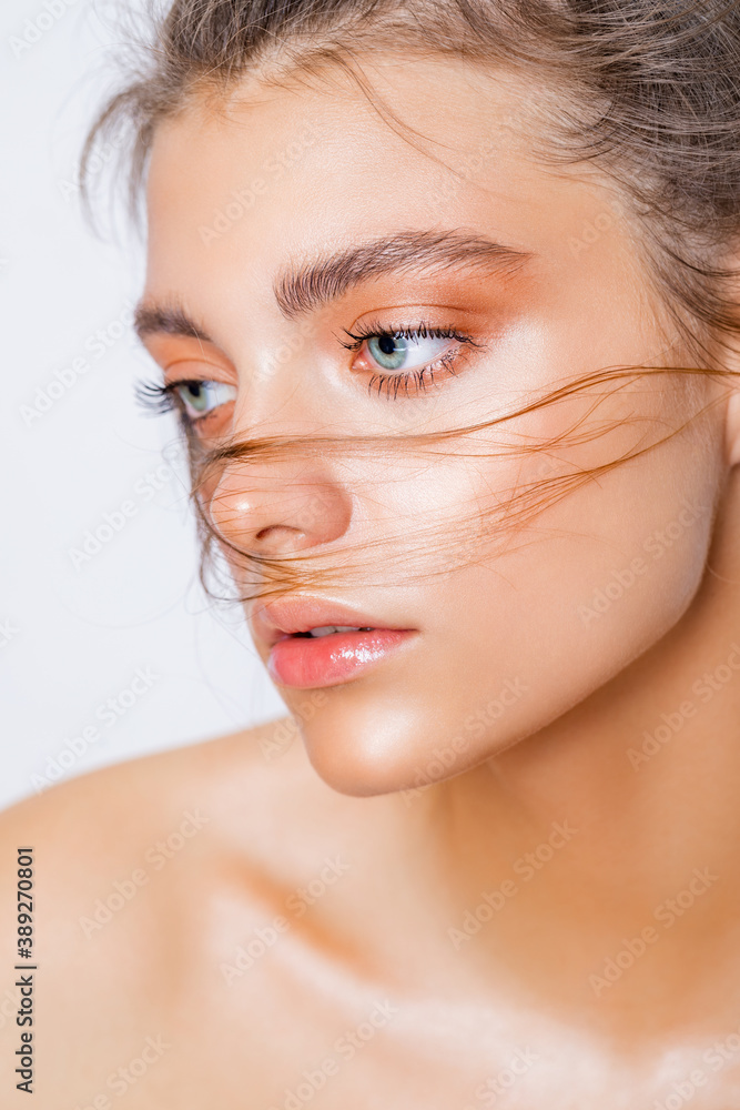 Foto Stock Beauty portrait of young caucasian model with natural make-up.  Fashion shiny highlighter on skin, gloss lips make-up. wet makeup. close-up  | Adobe Stock