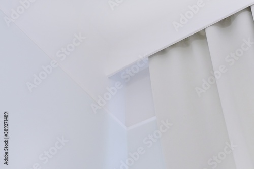 Interior details close up. White wall, ceiling, cornice niche, curtains on the window