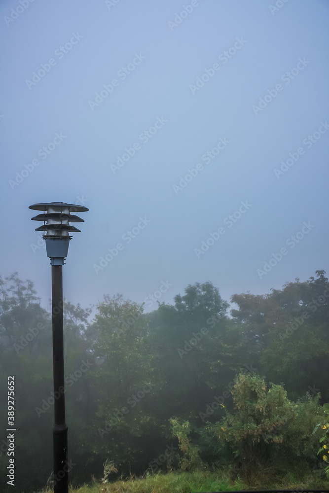 Foggy autumn morning of the Lviv City Center. Paved road and street lamp in the Lviv Park High Castle in the fog. Foggy autumn morning of the Lviv City Center. Paved road and street lamp in the Lviv Park High Castle in the fog.