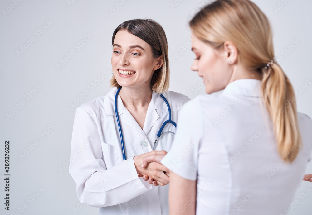 Happy woman doctor in medical gown with stethoscope and patient back view Happy woman doctor in medical gown with stethoscope and patient back view