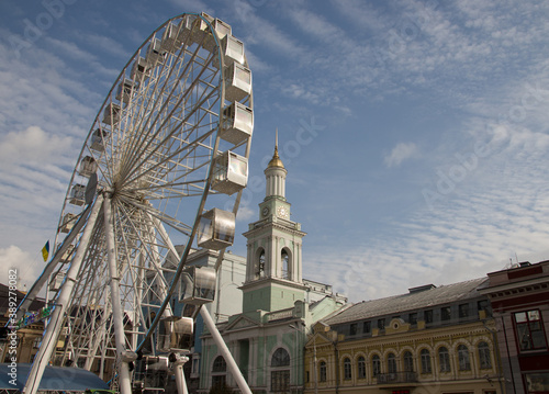 UKRAINE. KYIV - 24 OCTOBER 2020. A view of the old Bell Tower next to the modern ferris wheel, the Contract Square. Beautiful autumn blue sky with cirrus clouds