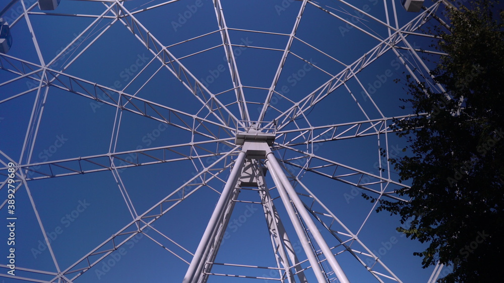 Obraz premium In the park, a large Ferris wheel is spinning slowly. High-altitude view wheel