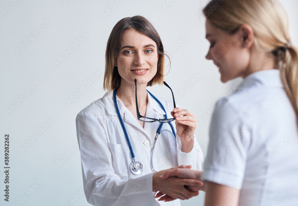 beautiful woman doctor with stethoscope shaking hands with female patient beautiful woman doctor with stethoscope shaking hands with female patient