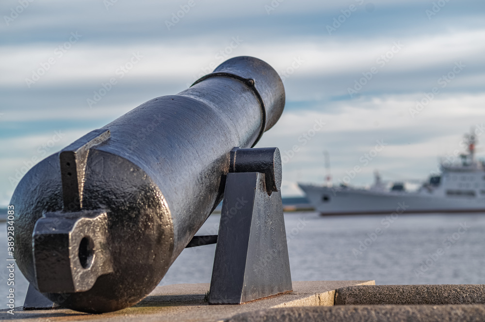 A medieval cannon cannon is aimed at a modern ship.
