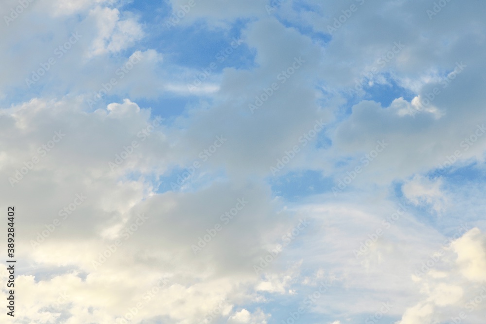 Light blue sky with light gray and white clouds in diffused light