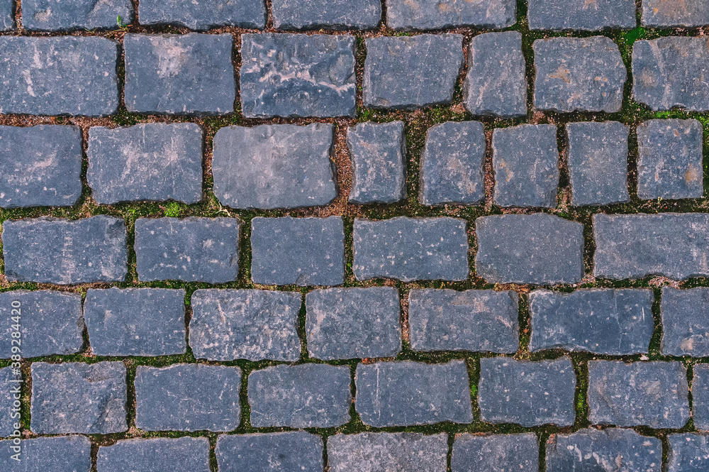 Cobblestone road for background and texture. Old road made of granite paving stones.