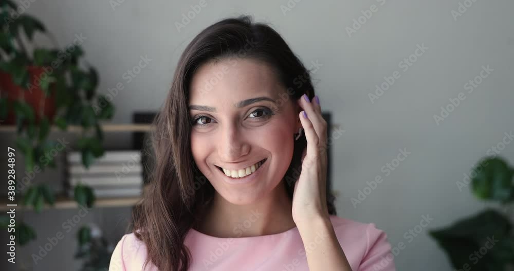 Close up head shot portrait of smiling beautiful young indian arabic ethnicity woman with perfect skin and healthy white toothy smile touching shiny hair, satisfied with beauty procedures service. Close up head shot portrait of smiling beautiful young indian arabic ethnicity woman with perfect skin and healthy white toothy smile touching shiny hair, satisfied with beauty procedures service.