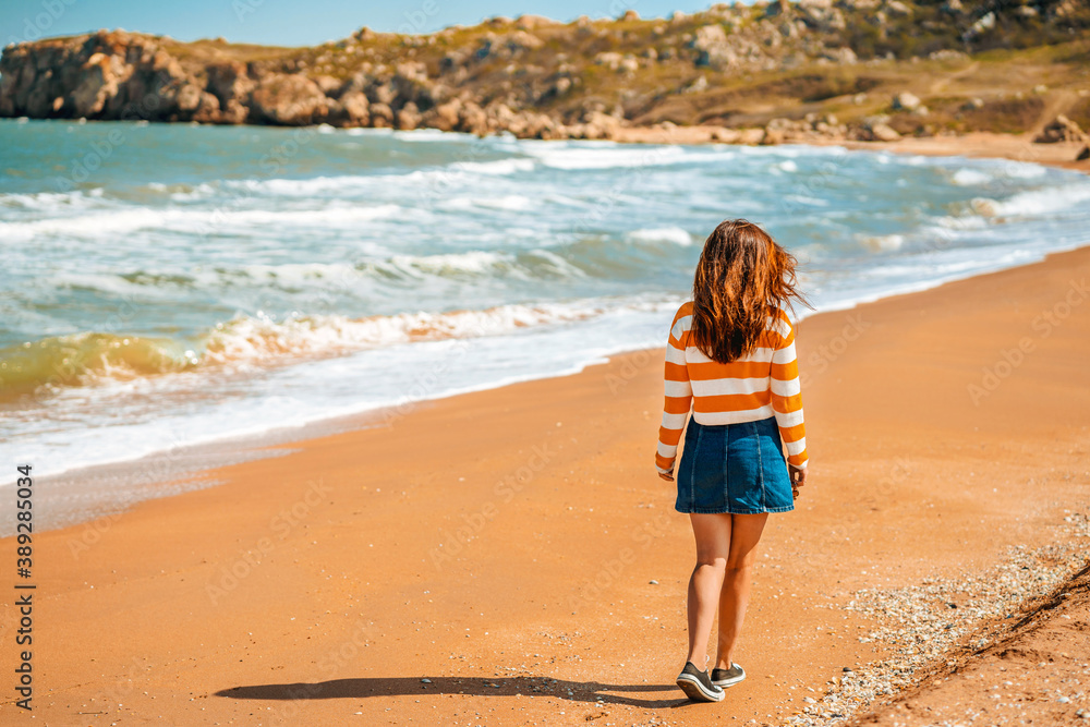 Beautiful young woman with long hair walks along the Black sea on the beach