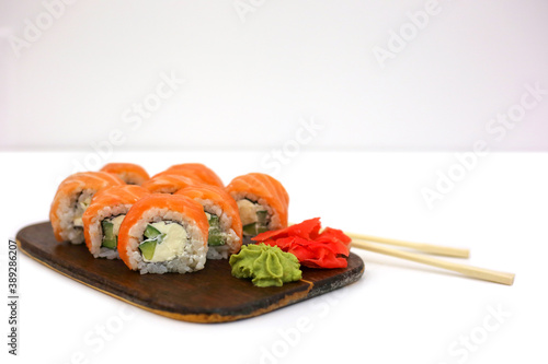 Philadelphia rolls with salmon on white table next to chopsticks, wasabi and ginger. Sushi menu. Japanese food concept. Place for text