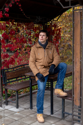 Young white man in casual clothes in autumn on a walk in the park.