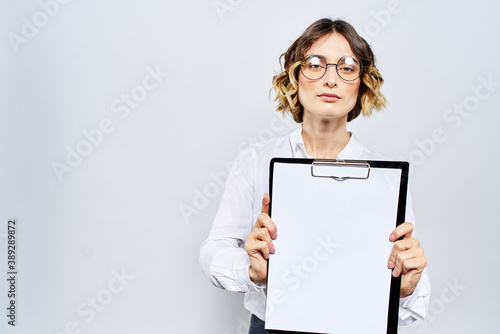 Business woman with a folder of white documents in her hand on a light background And hairstyle glasses model