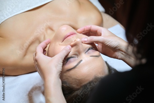 Mature woman face massage, beautician doing facial spa treatments