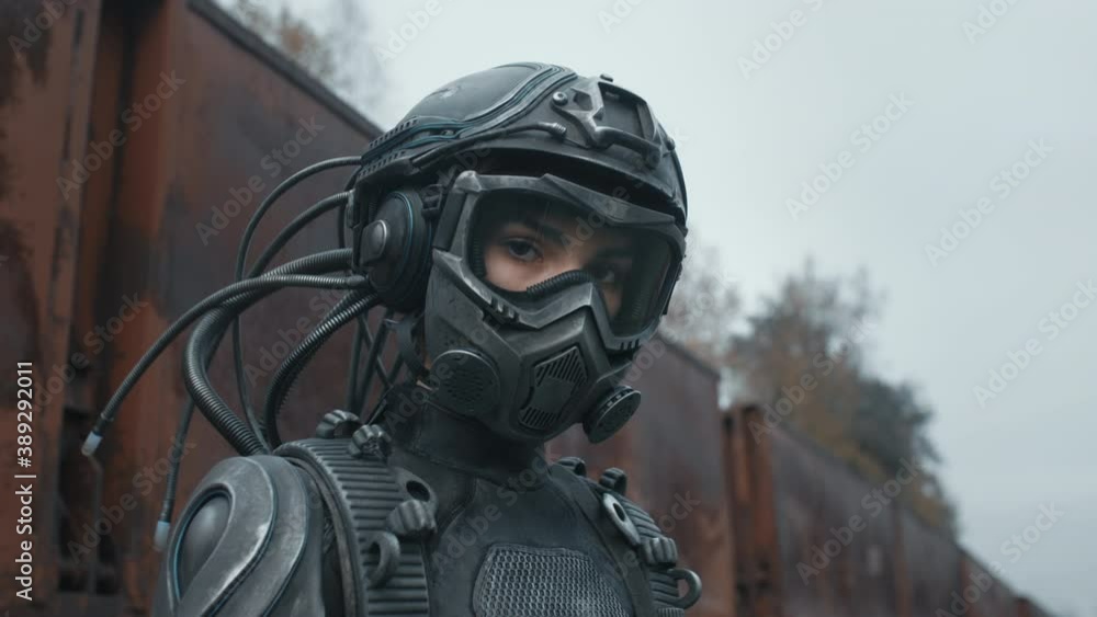 Portrait female future soldier in fiction helmet standing by rusty train carriage after nuclear war. Lonely star trooper cyborg girl in futuristic combat suit. Cyberpunk military post apocalypse Portrait female future soldier in fiction helmet standing by rusty train carriage after nuclear war. Lonely star trooper cyborg girl in futuristic combat suit. Cyberpunk military post apocalypse