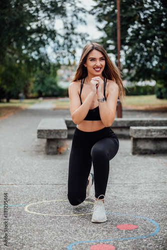 Young attractive sportswomen work outdoor. Fitness woman stretching her legs before jogging and training. 