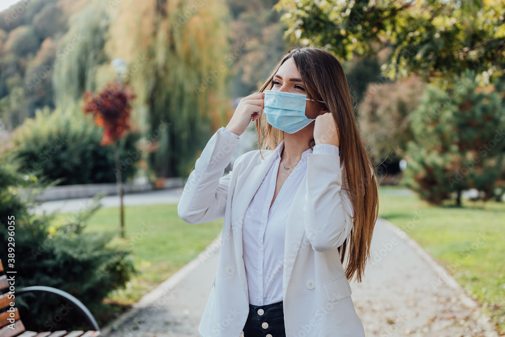 A beautiful businesswoman puts a surgical mask on her face. Prevention of coronavirus.