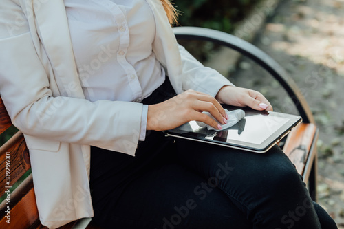 Beautiful businesswoman cleaning a tablet outdoor with wet wipes. photo