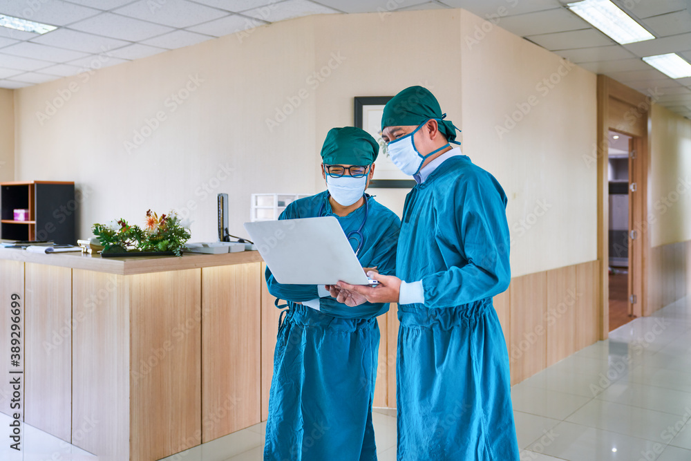Two doctor in surgery suit discussing with laptop in clinic healthcare