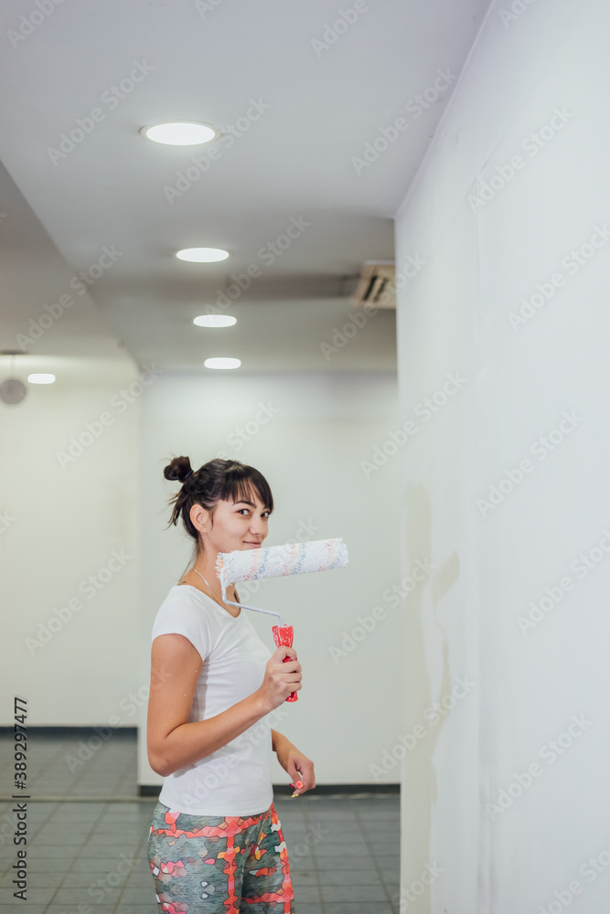 Beautiful girl painting the wall with a roller. Interior renovation Beautiful girl painting the wall with a roller. Interior renovation