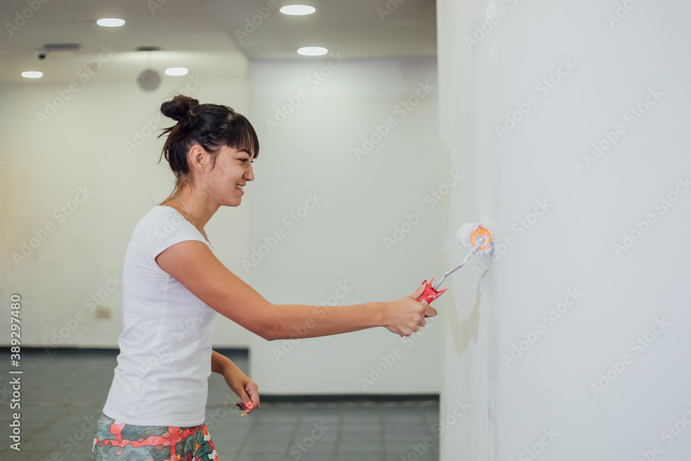Beautiful girl painting the wall with a roller. Interior renovation Beautiful girl painting the wall with a roller. Interior renovation
