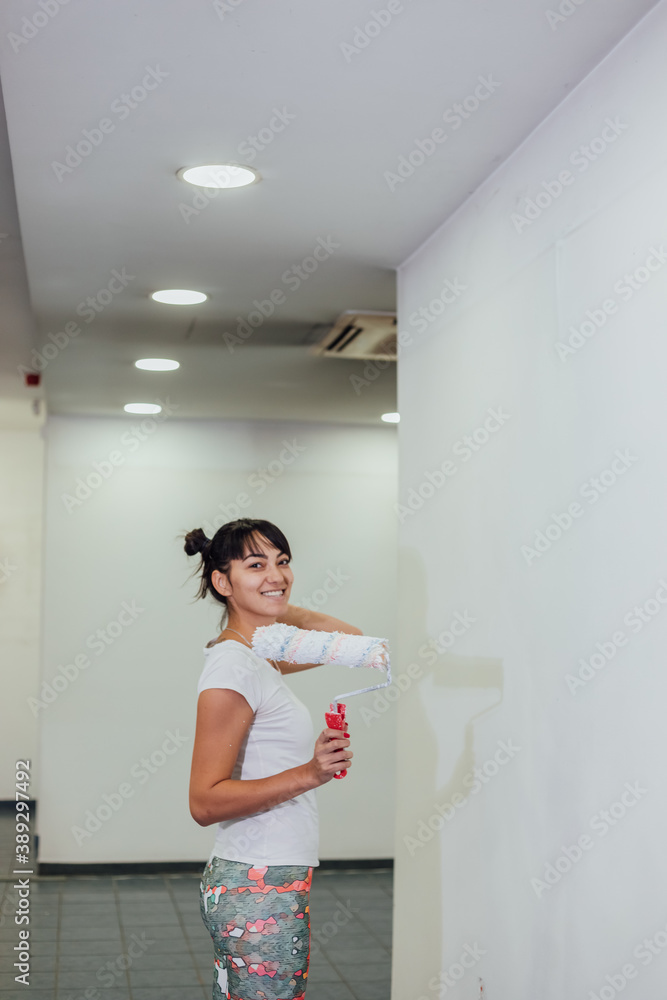 Beautiful girl painting the wall with a roller. Interior renovation Beautiful girl painting the wall with a roller. Interior renovation