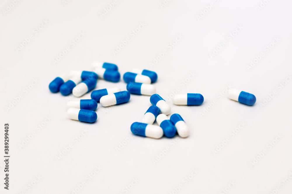 Photo close-up of blue medical capsules grouped in center on a white background. The concept of helping with pain, poisoning, and high temperature. Dosage of medications Photo close-up of blue medical capsules grouped in center on a white background. The concept of helping with pain, poisoning, and high temperature. Dosage of medications