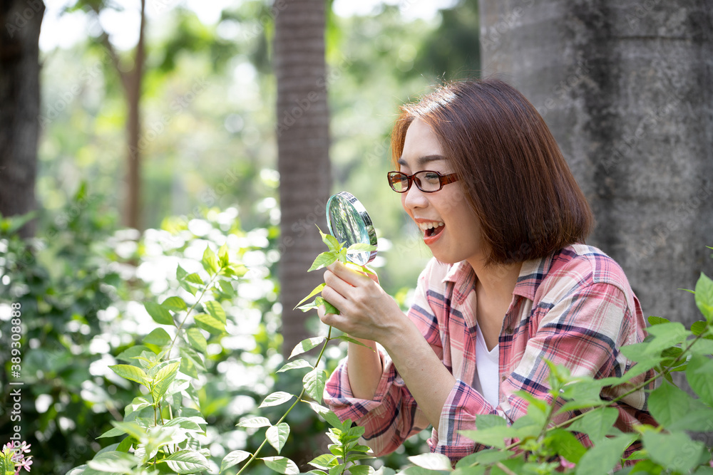 Beautiful asian scientist uses a magnifying glass to study plant and natural in the garden. Concept of plant research and propagation. Beautiful asian scientist uses a magnifying glass to study plant and natural in the garden. Concept of plant research and propagation.